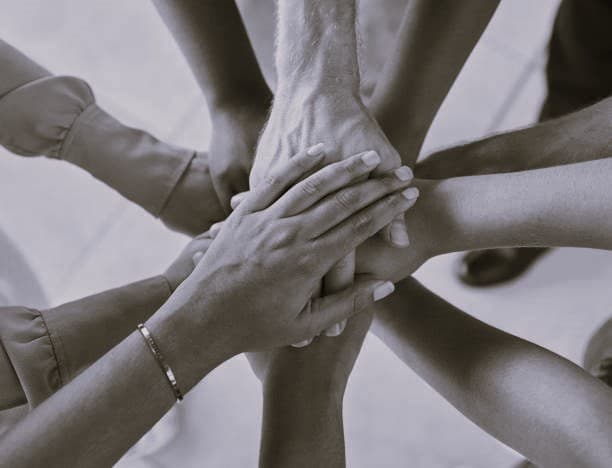 CleanQuest team members joining hands in unity